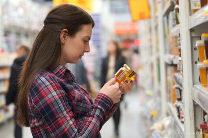 Una mujer lee el etiquetado de un bote de miel.