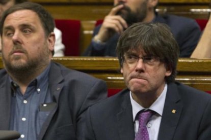 Puigdemont y Junqueras, en el Parlament, con gesto serio.