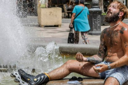 Un hombre se refresca en una fuente del centro de Valencia para soportar las altas temperaturas, a 12 de julio de 2021, en Valencia, Comunidad Valenciana (España).