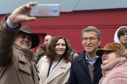 La presidenta de la Comunidad de Madrid, Isabel Díaz Ayuso, y el líder del PP, Alberto Núñez Feijóo, se hacen fotos con simpatizantes durante un paseo por la Plaza Mayor.