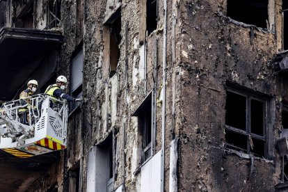 Bomberos en una grúa sanean la fachada quemada