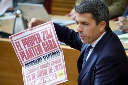 Carlos Mazón, president de la Generalitat, con un cartel electoral de la CUP las pasadas elecciones