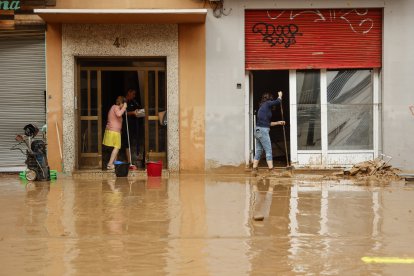 Varias personas limpian la zona afectada por el temporal