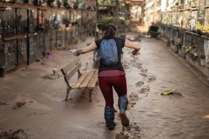 Una mujer anda entre el barro en el cementerio de Alfafar