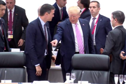 Donald Trump le señala a Pedro Sánchez su sitio en la cumbre del G20 en Osaka en 2019.