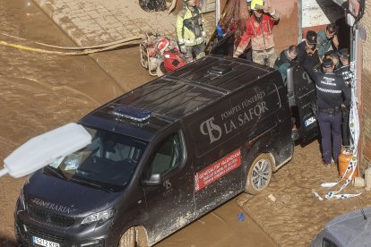 Un furgón de la funeraria sale de un garaje con cadáveres localizados tras el paso de la DANA