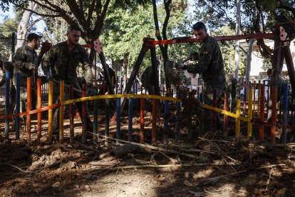 Varios militares realizan labores de limpieza en un parque infantil.