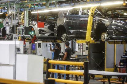 Archivo - Dos trabajadores con un vehículo en una fábrica.