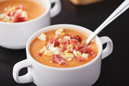 Taza blanca de salmorejo tradicional con jamón ibérico y huevo duro picado