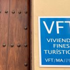 Puerta de una vivienda turística en Málaga con el cartel indicativo de licencia de 'Vivienda con Fines Turísticos'.