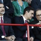 Felipe VI, en un gesto pensativo, mientras Sánchez y Torra conversan.