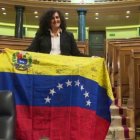 Una opositora venezolana al colocar este jueves una bandera de su país en el escaño de Pablo Iglesias.