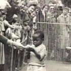 Visitantes intentando acariciar a una niña negra, en un zoo humano de Bélgica en 1958