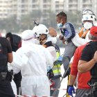 Un miembro de la Cruz Roja ayuda a bajar del barco a un niño migrante en el puerto de Arguineguín, Gran Canaria.