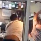 Momento en el que un hombre lanza una silla contra otras personas dentro del bar durante la pelea