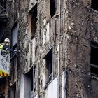 Bomberos en una grúa sanean la fachada quemada