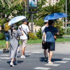 Imágenes de personas al lado de un termómetro en las calles de Sevilla en julio.