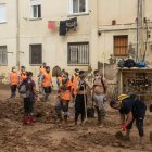 Voluntarios y vecinos retiran barro con palas, en el barrio de El Raval, en Algemesí.