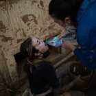 Una mujer da agua a otra mientras saca agua y barro de un sótano afectado por la DANA, a 10 de noviembre de 2024, en Catarroja.