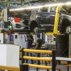 Archivo - Dos trabajadores con un vehículo en una fábrica.