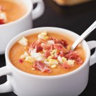 Taza blanca de salmorejo tradicional con jamón ibérico y huevo duro picado
