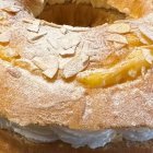 Primer plano de la Corona de la Almudena, donde se aprecia la textura del brioche, la crema y el acabado con almendras y azúcar glas.