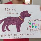 Niña sostiene el dibujo de un perro