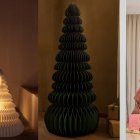 Diferentes versiones del árbol navideño de papel: blanco con luz integrada, verde oscuro escultórico y terracota con regalos, ideales para salones con estética minimalista.