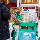Un vendedor de lotería ofrece boletos del sorteo navideño y juegos de rasca en una céntrica calle comercial, donde muchos españoles prueban suerte cada diciembre.