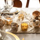 Una mesa festiva con detalles dorados y velas suaves: el escenario perfecto para servir el aperitivo navideño inspirado en el chef Ángel León.