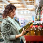 Mujer observa botella de aceite en el supermercado