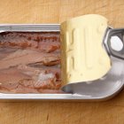 Una lata de anchoas, presentada en aceite, revela la textura carnosa y brillante que enamora a los expertos del laterío fino.