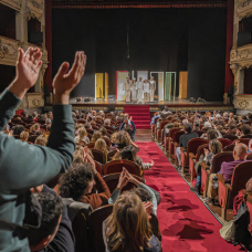El patio de butacas de un teatro aplaude tras una función.