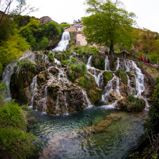 La cascada atraviesa Orbaneja del Castillo en terrazas turquesa hacia el Ebro.