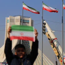 Un niño iraní sostiene una bandera de su país cerca de los misiles de fabricación iraní en la plaza Azadi (libertad) de Teherán.