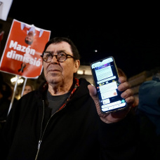 Un hombre muestra la alerta en su móvil durante una manifestación en contra de Mazón