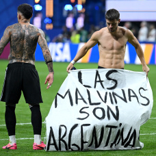 ATLANTA, GEORGIA - JULY 15: Giovani Lo Celso #11 of Argentina holds a banner after the 2-1 win during the FIFA World Cup 2026 Semi Final match between England and Argentina at Atlanta Stadium on July 15, 2026 in Atlanta, Georgia. The banner refers to the British Overseas Territory of the Falkland Islands, located off the coast of Argentina. Argentina disputes British sovereignty over the islands and refers to them as Las Malvinas. (Photo by Shaun Botterill/Getty Images)