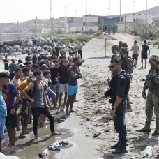 Policía Nacional y el Ejército ante un grupo de los miles de inmigrantes que han cruzado a nado desde Marruecos hasta Ceuta