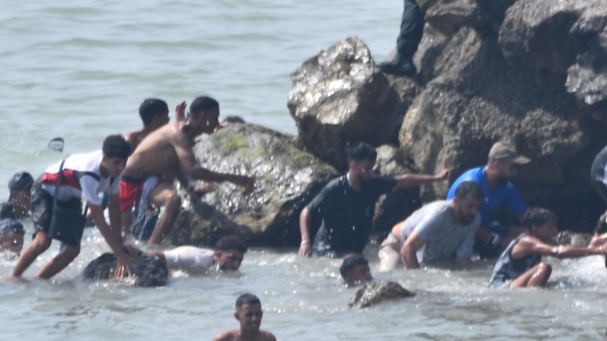 Varias personas intentan cruzar la frontera a nado, a 30 de julio de 2026, en Ceuta (España).