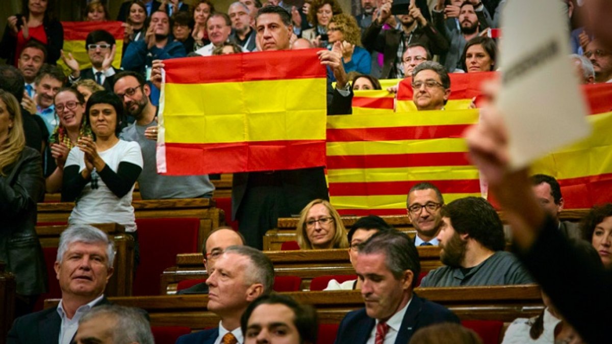 El líder del PP catalán sostiene una bandera de España en el Parlament.