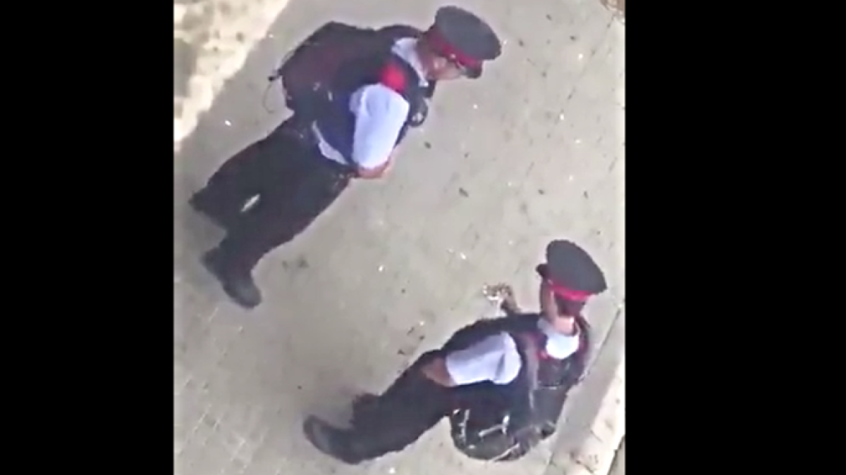 El Mosso se come el bocadillo tranquilamente y frente a ellos el colegio con gente votando.