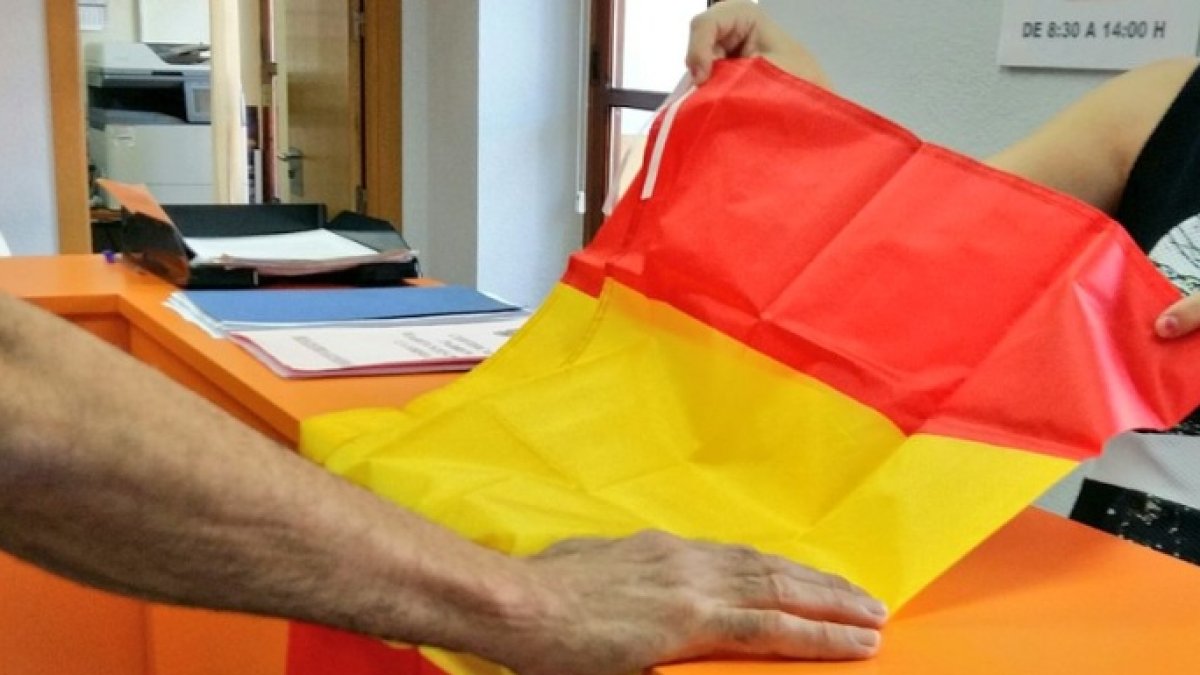 Un vecino de Archena (Murcia) recoge una bandera de España en el Ayuntamiento.