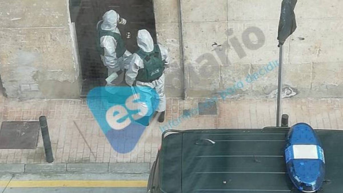 Dos agentes del GEAR, equipados con trajes especiales, se dispone a entrar en uno de los domicilios en cuarentena.