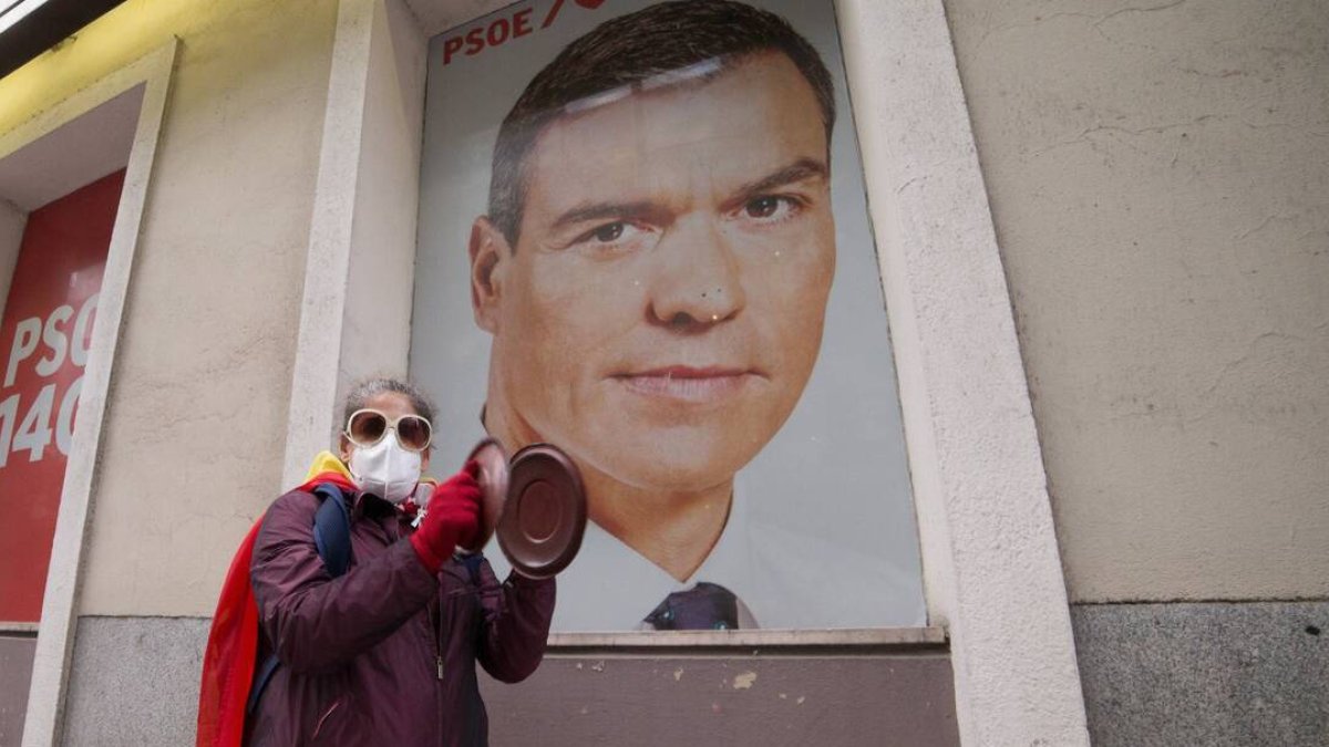 Una mujer protesta frente a un retrato de Sánchez