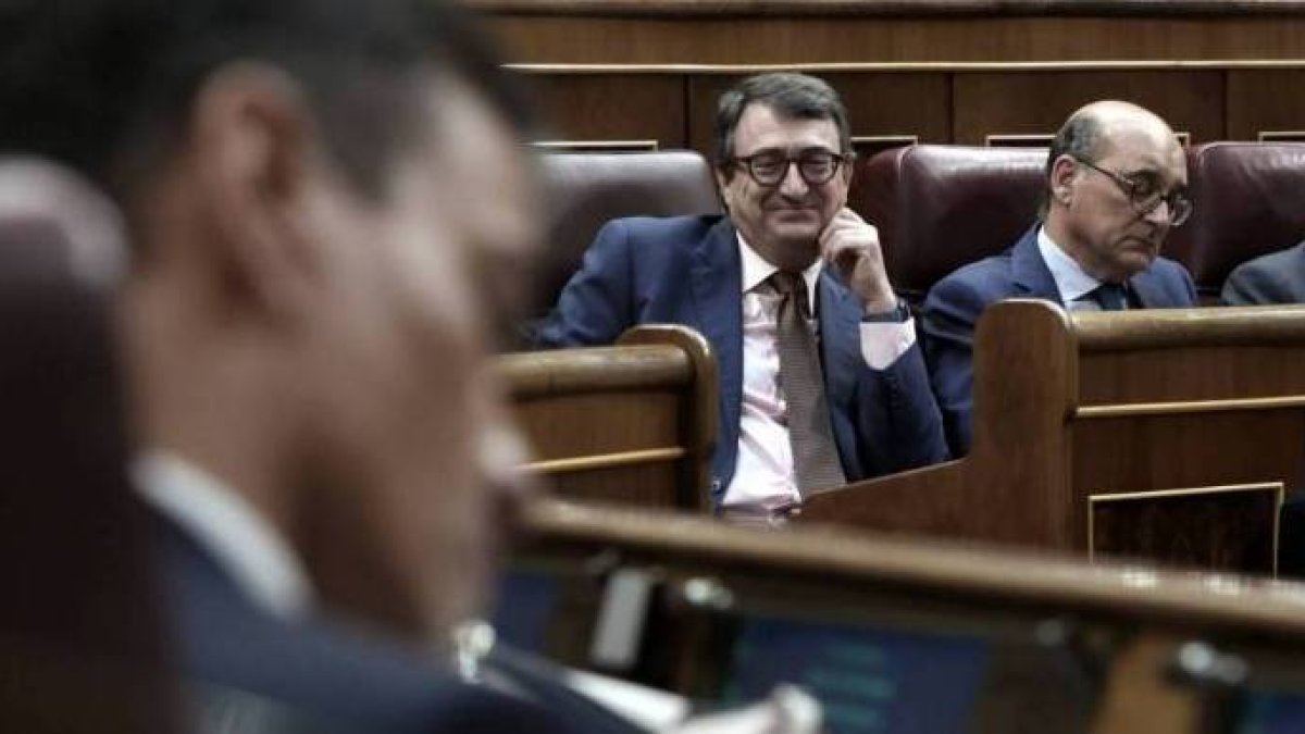 El portavoz del PNV, Aitor Esteban, mira sonriendo a Sánchez en su escaño.