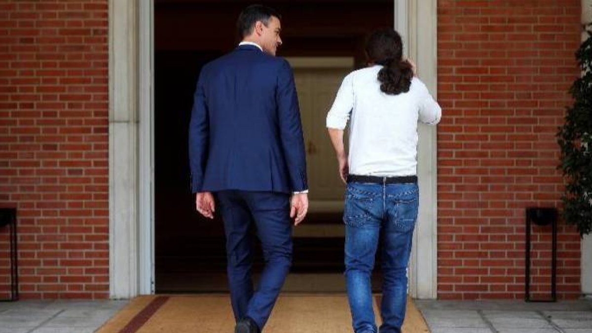 Sánchez e Iglesias, de espaldas, entrando en el Palacio de la Moncloa.