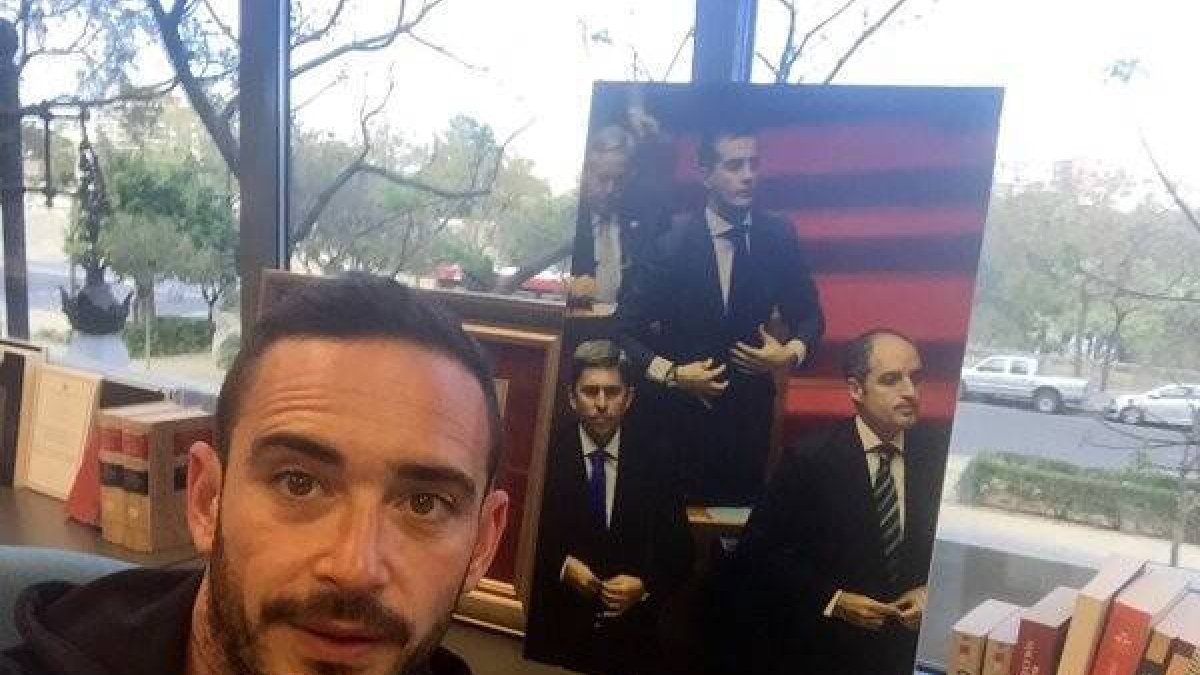 El periodista con un cartel de ex dirigentes del PPCV que sirvió pra ilustrar una entrevista en Soma Comunicación.