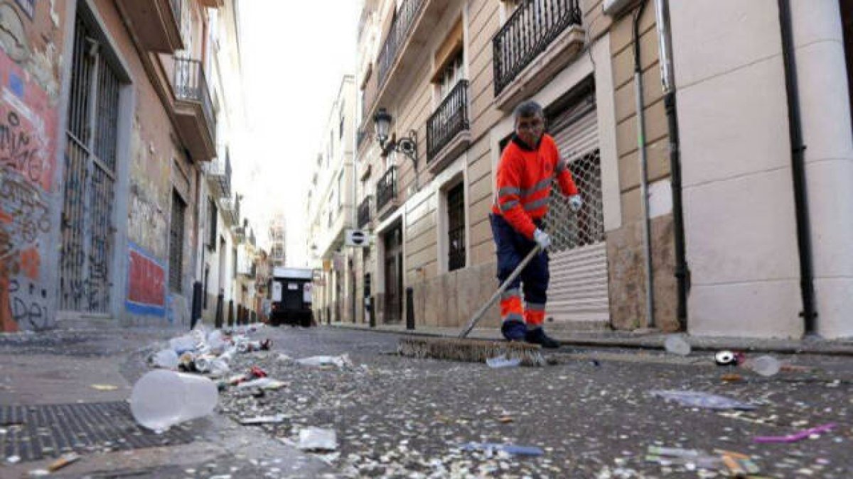 Una operario limpia una calle sucia de Valencia