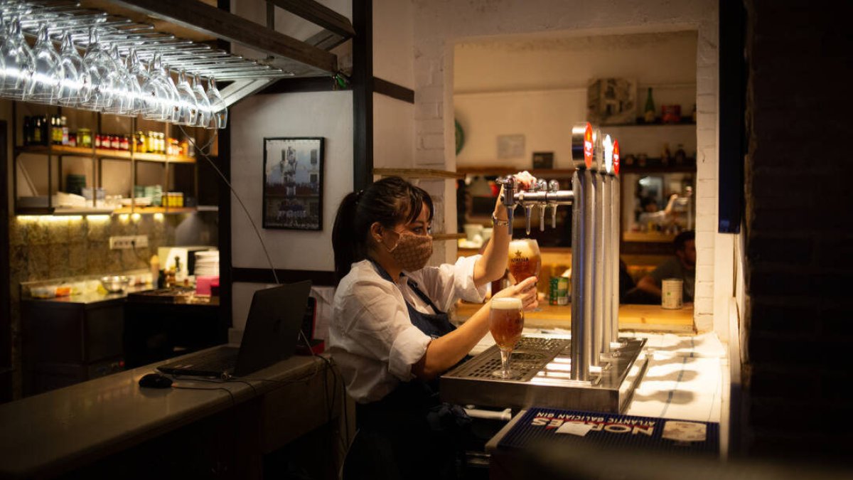 Camarera sirviendo una cerveza en el interior de un bar