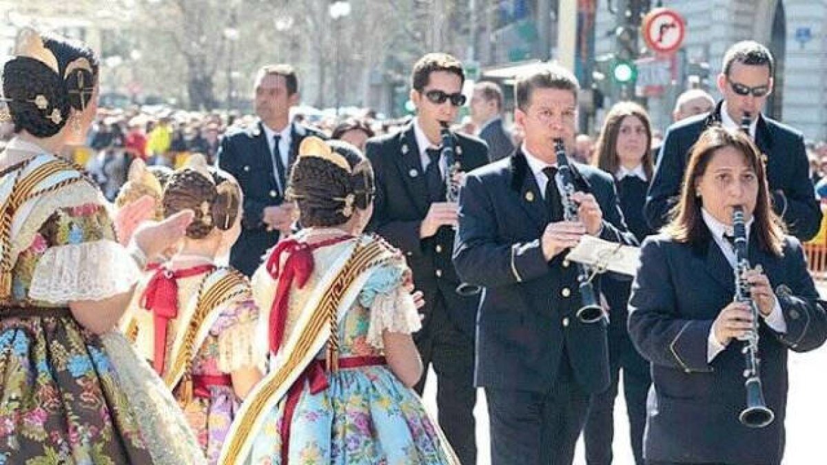 Banda de música desfila ante unas falleras